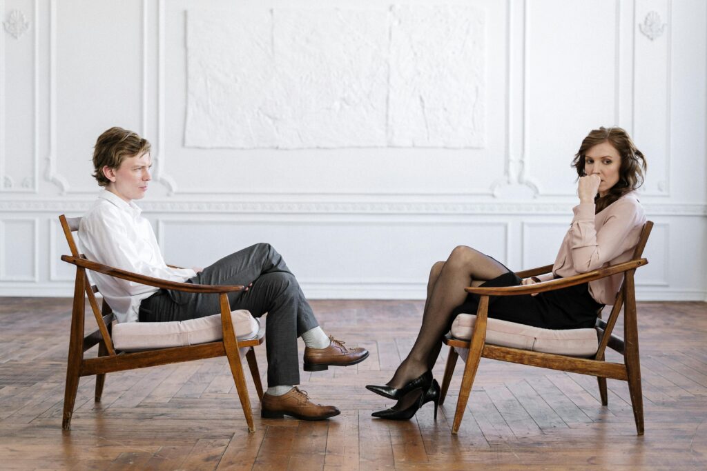 Man and woman in professional consultation setting, sitting across each other in modern office.