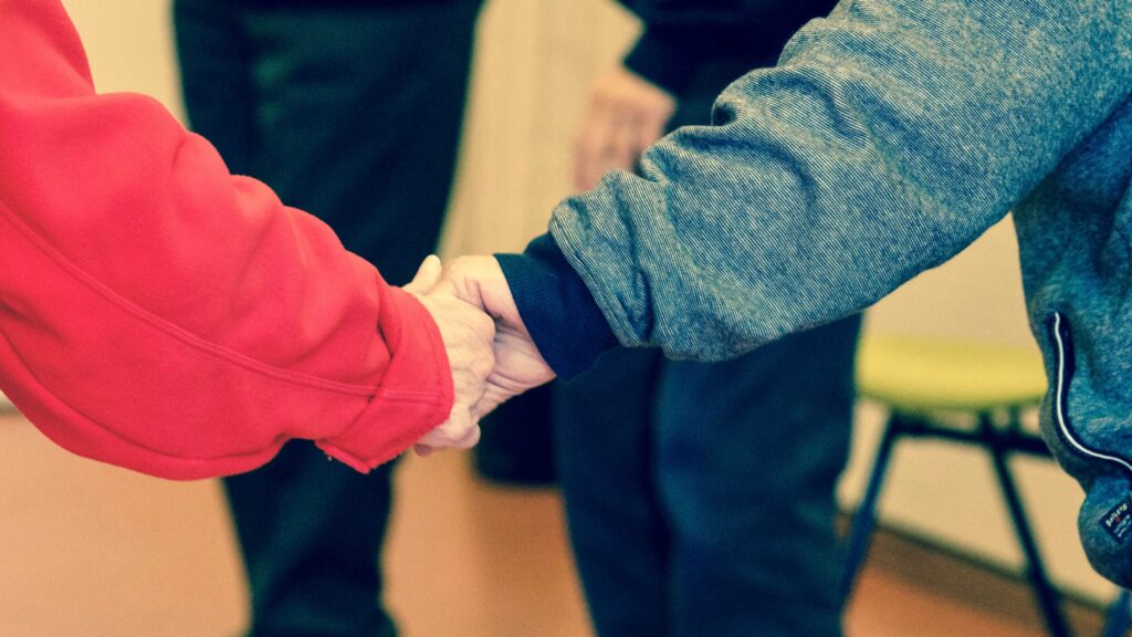 Close-up of elderly hands holding, symbolizing friendship and support indoors.